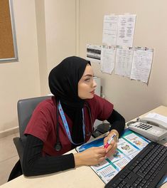 a woman with a headscarf sitting at a desk in front of a computer