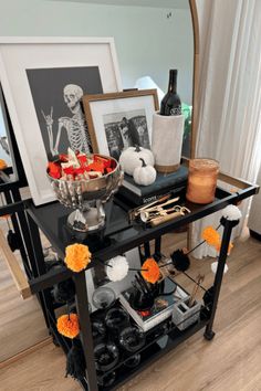 a black table topped with pictures and vases filled with orange flowers sitting on top of a hard wood floor