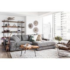 a living room filled with furniture and a large window covered in lots of natural light