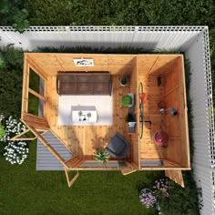 an aerial view of a small wooden house in the middle of some grass and flowers