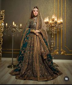 a woman in a green and gold bridal gown standing next to a chandelier