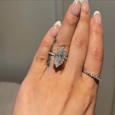 a woman's hand holding an engagement ring with a diamond on it and the other hand