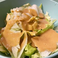 a blue bowl filled with lettuce and dressing