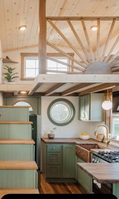 a kitchen with green cabinets and wooden stairs