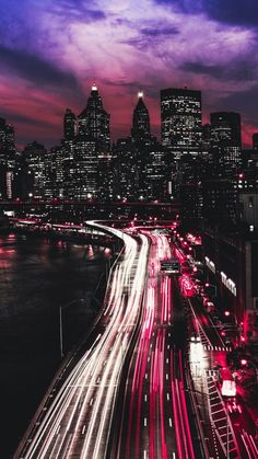 the city skyline is lit up at night with bright lights and streaks of light in the foreground