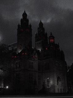 an old building with red lights in the windows and dark clouds above it at night