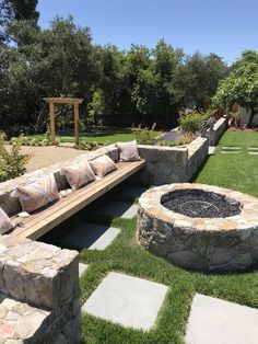 an outdoor seating area with stone benches and fire pit