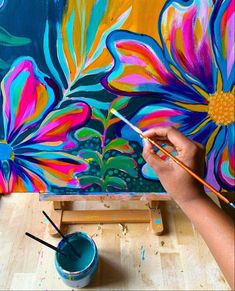 someone is painting flowers on a canvas