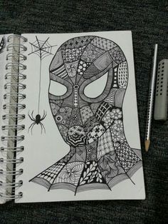 a notebook with a drawing of a spiderman on it and a pen next to it