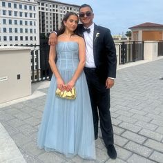 a man in a tuxedo and a woman in a blue dress pose for a photo