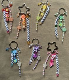 six keychains with beads and charms on them sitting on a cloth covered surface