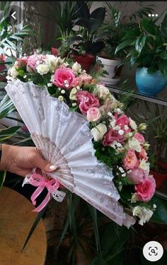 a person holding an umbrella with flowers on it and pink ribbon tied around the handle