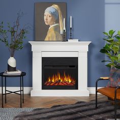 a living room with blue walls and a painting on the wall above an electric fireplace