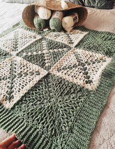 a crocheted blanket with balls of yarn on top of it and a hat