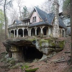 an old house built into the side of a cliff with a cave in front of it