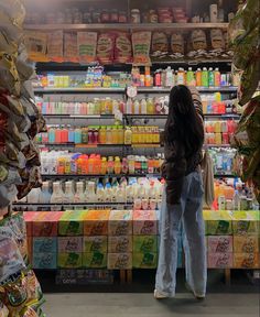 a woman standing in front of a store filled with food