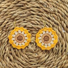 two yellow and white crocheted earrings sitting on top of a wicker basket