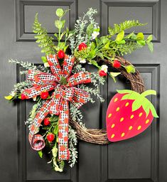 a wreath with strawberries and greenery is hanging on the front door to give as a decoration