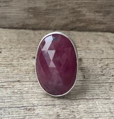 A stunning large oval deep red faceted raw sapphire has been set in sterling silver with a handmade ring band from sterling silver half dome wire. This stone is 23mm x 15mm in size and is a deep red with smaller darker accents throughout the stone. The faceted cut on the surface of the raw sapphire helps it catch the light and sparkle. There is 1 sister stone that can be made into a ring of any size! Stock Ring Size 8.25-8.75 ONLY. Made to order ring can be any size! Sapphires are the birthstone Pink Ruby Ring In Sterling Silver, Pink Oval Ruby Ring In Sterling Silver, Silver Oval Ruby Ring With Large Stone, Oval Faceted Ruby Ring For Anniversary, Oval Ruby Ring With Large Stone In Silver, Sapphire Ring Engagement, Engagement Ring Raw, Raw Sapphire, Raw Stone Ring