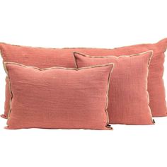 three coral colored pillows with tan piping on the front and back, one is made from