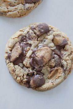 two cookies with chocolate chips and peanut butter in them on a white tablecloth surface