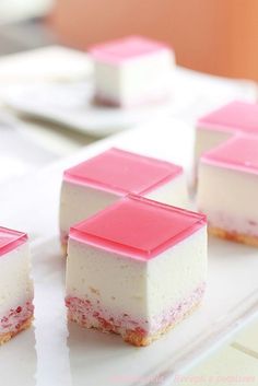 four pieces of cake sitting on top of a white plate with pink and white frosting