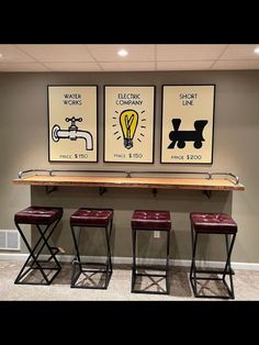 three framed posters on the wall above stools in a room with carpeted flooring