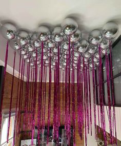 purple streamers hanging from the ceiling in front of a brick wall and mirror balls