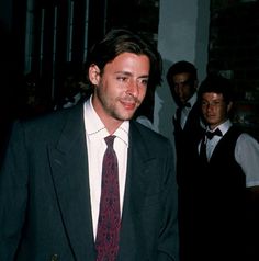 a man in a suit and tie walking down the street with other men behind him