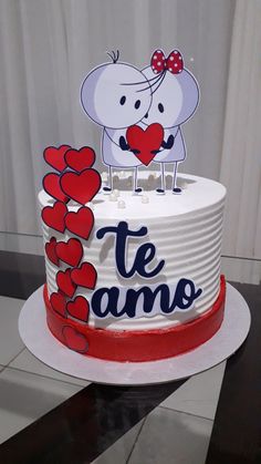 a white cake with red hearts and an elephant on top that says te amo