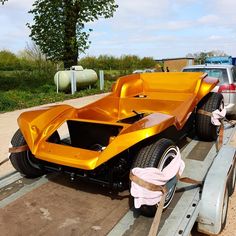 an orange car is being towed on a flatbed trailer