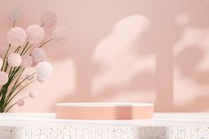 a vase filled with flowers sitting on top of a white shelf next to a pink wall