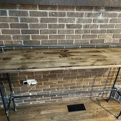 a shelf made out of metal pipes and wooden planks in front of a brick wall