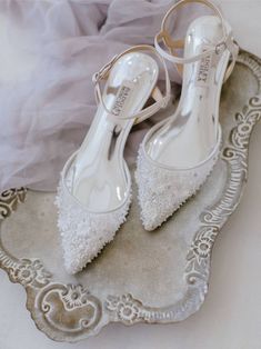 a pair of white shoes sitting on top of a silver tray next to a veil