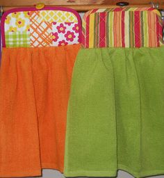 three towels are hanging on a rack in the kitchen, one is orange and green