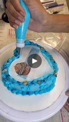 a person is decorating a cake with blue icing