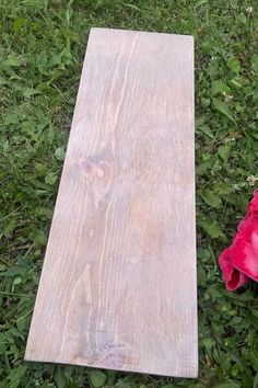 a piece of wood laying on the ground next to a pink flower and some green grass