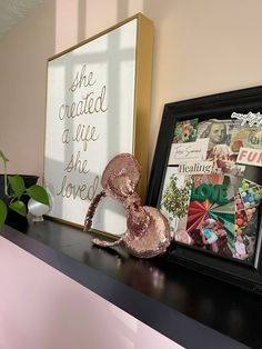 there is a framed picture on the mantle next to a pink vase with flowers in it