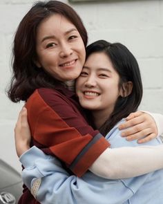 two women hugging each other in front of a building