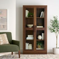 a living room with a green chair and wooden bookcase in front of a white wall