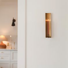 a wall mounted candle on the side of a white wall next to a kitchen counter