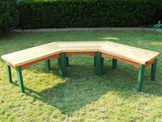 a wooden bench sitting in the middle of a grass covered field next to a hedge