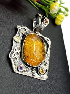 "Artisan Amber gemstone pendant Hand-made Sterling Silver. Stones used: Amber, Peridot, Amethyst, Garnet, Citrine. Height - 51mm, Width - 34mm. Unique Handcrafted One-of a-kind Design Pendant Each Piece of Jewelry in my Collection is Absolutely One of a Kind! When you start wearing a piece of my jewelry you will fall in love with it more and more each day and feel that good Energy and Love that I pass into it while creating this piece of Art. A piece of Art created for you to be inspired and lov Handmade Fusion Citrine Jewelry, Handmade Amber Necklace For Anniversary, Yellow Jewelry With Artistic Design For Gifts, Fusion Style Pendant Jewelry As A Gift, Fusion Style Pendant Jewelry For Gifts, Fusion Style Pendant Jewelry Gift, Unique Yellow Jewelry With Artistic Design, Unique Artistic Yellow Jewelry, Artistic Handmade Jewelry For Celebration