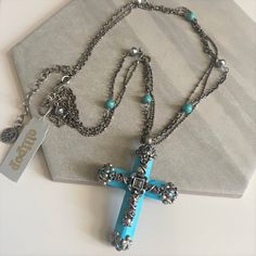 "Vintage 1990s Gothic style magnesite? turquoise cross pendant necklace. Stunning exquisite cross has  silver tone filigree detailing of vines, leaves, flowers and scrolls with glass crystal accents. I believe  the cross is made of magnesite, a mineral that has turquoise color. The cross comes on a 3 strand silver tone chain accented with round turquoise beads and antiqued silver tone beads. It is NOS (new old stock) with the original Olipop paper tags. Olipop is a division of Sweet Romance and Bohemian Turquoise Cross Necklace, Blue Bohemian Necklace With Cross Pendant, Bohemian Blue Cross Pendant Necklace, Adjustable Turquoise Cross Jewelry, Silver Turquoise Cross Necklace For Gift, Boho Charm Bracelet, Turquoise Cross Necklace, Vines Leaves, Turquoise Cross Pendant