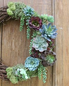 a wreath with succulents and greenery is displayed on a wooden surface