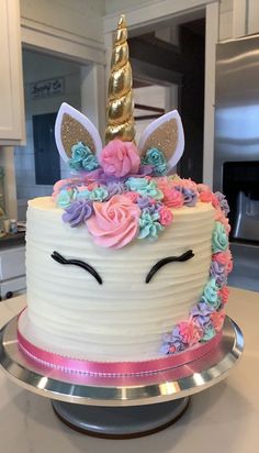 there is a cake decorated with flowers and a unicorn face on the top of it