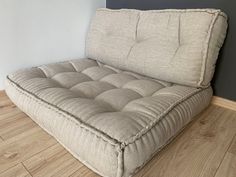 a couch that is sitting on the floor in front of a wall and hardwood floors