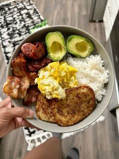 a person holding a plate with eggs, bacon, and avocado