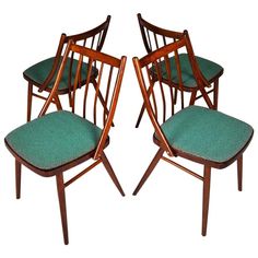 a set of four chairs with green upholstered seat cushions on each one side