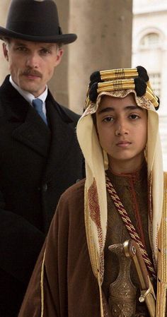 a man and woman dressed in traditional clothing standing next to each other on the street